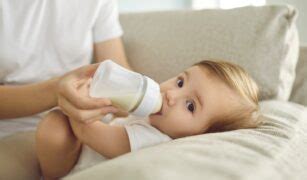 Bebeluș bucuros care bea lapte dintr-un biberon