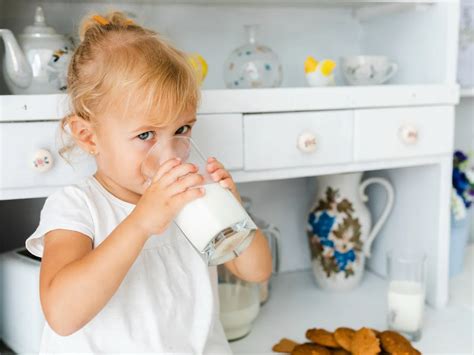 Copil mic savurând lapte dintr-o canuță