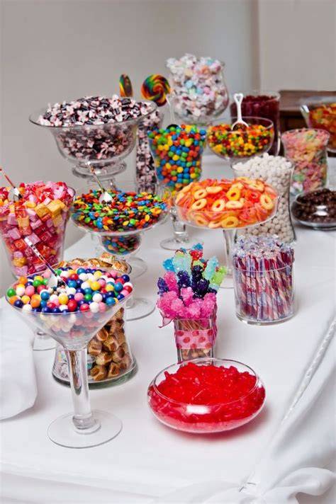Imaginea unui candy bar bine organizat cu suporturi diferențiate pe înălțimi, boluri colorate și panou personalizat