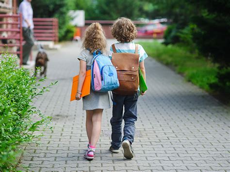 Adolescentă mergând spre școală cu un copil în brațe