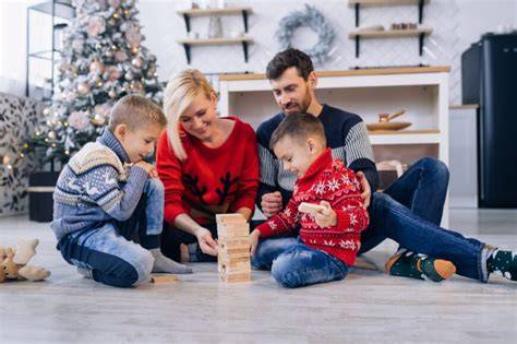 Imaginea unei familii care se joacă în interior cu cuburi mari și materiale pentru colaje