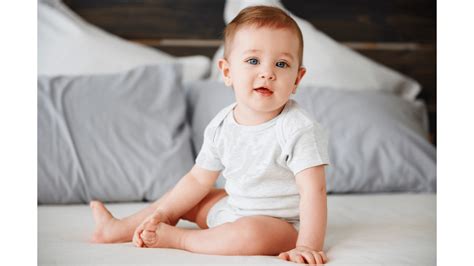 Bebelus exersand statul in sezut cu ajutorul parintelui