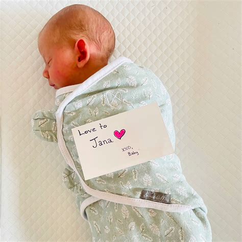 Fotografie cu o mamă care își ține bebelușul în brațe, amândoi zâmbind.