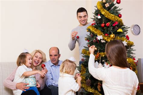 Familie sarbatorind Craciunul in fata bradului impodobit