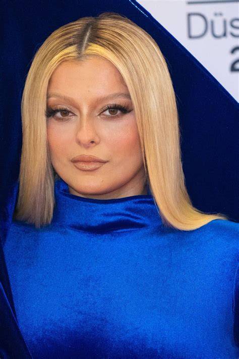 Portretul Bebe Rexha pe covor roșu și etichete de carieră