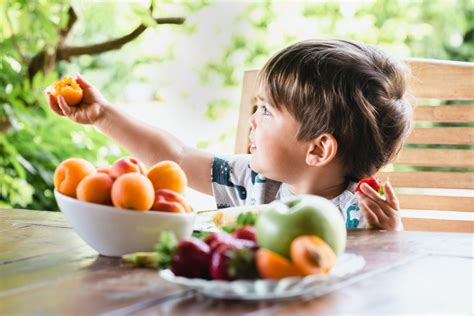 Copil fericit mâncând fructe proaspete