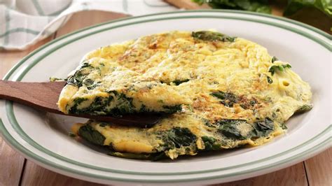 O tigaie cu o omletă de spanac și brânză pe jumătate pliată