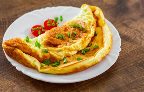 O imagine cu o omletă pufoasă tăiată în bucăți mici, alături de legume mici
