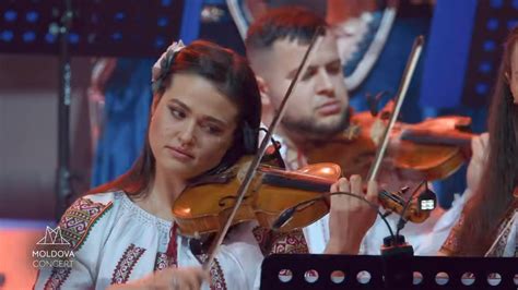 Imagine cu Emilia Ghinescu pe scena unui concert de muzică populară, costum tradițional, în lumina reflectoarelor